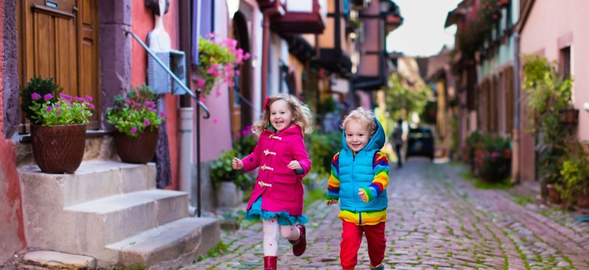 two young children running downa cobbled street
