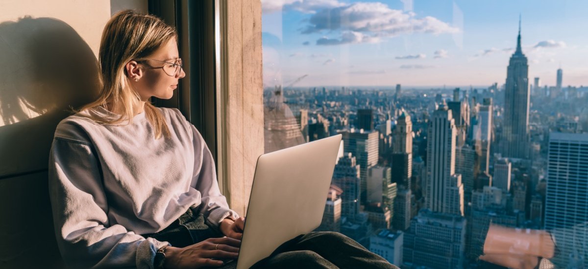 woman-on-a-laptop-looking-out-in-new-york-skyline